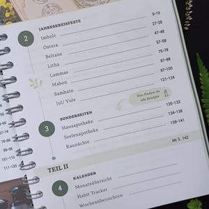 May include: A green and white planner with a spiral binding. The cover features a floral design and the text "JAHRESKREISFESTE" and "TEIL II". The planner includes sections for "Sonderseiten", "Kalender", "Monats&uuml;bersicht", "Habit Tracker", and "Wochen&uuml;bersichten".