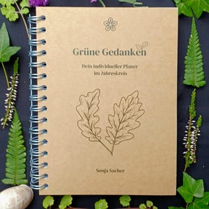 May include: A brown spiral bound journal with the title "Gr&uuml;ne Gedanken" and the text "Dein individueller Planer im Jahreskreis" and the author "Sonja Sacher". The cover features a stylized drawing of two oak leaves.