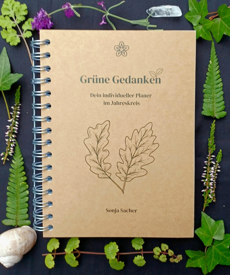 May include: A brown spiral bound journal with the title "Gr&uuml;ne Gedanken" and the text "Dein individueller Planer im Jahreskreis" and the author "Sonja Sacher". The cover features a stylized drawing of two oak leaves.