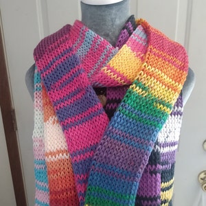 May include: A colorful striped knitted scarf with a variety of colors including pink, purple, blue, green, yellow, orange, and white.