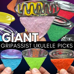 May include: A set of six colorful ukulele picks with a metal rim and a felt backing. The picks are labeled "GIANT GRIPASSIST UKULELE PICKS".