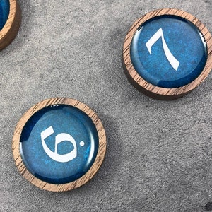 May include: Four wooden game pieces with blue resin tops and white numbers. The numbers are 1, 6, 7, and 8.