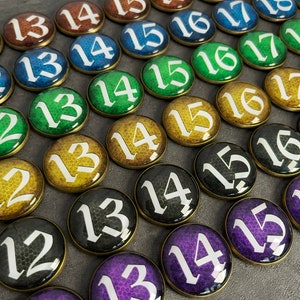 May include: A collection of round, colorful game pieces with white numbers from 12 to 19. The pieces have a textured surface and are arranged in rows.