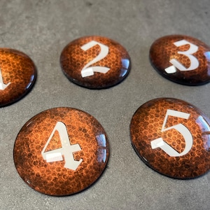 May include: Five round, orange-brown, textured, numbered game pieces with white numbers 1 through 5.