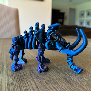 May include: A blue 3D printed skeletal model of a mammoth with a textured surface. The model is posed standing on all four legs with its trunk raised.
