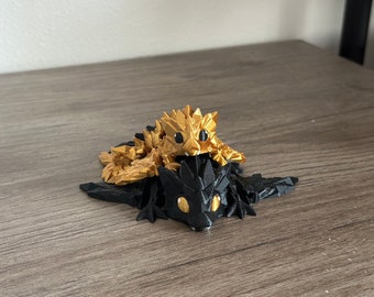 May include: A black and gold dragon figurine with a smaller gold dragon figurine on top. The dragons have detailed scales and large eyes.