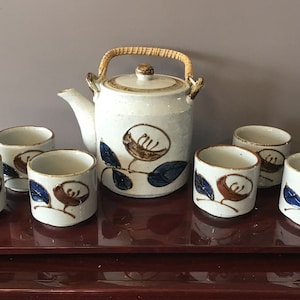 Earthenware Sandy Colored Teapot With Wicker Handle and 6 Tea Cups Decorated with Abstract Flower in Blue and Brown