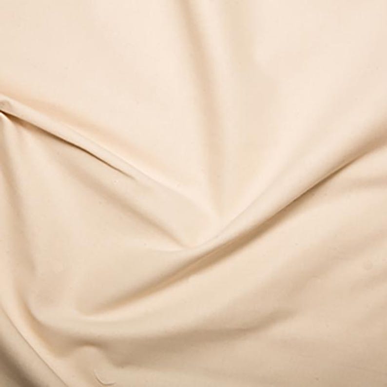 May include: A close-up of a smooth, off-white fabric with a soft, natural texture. The fabric is folded and draped, showcasing its drape and flow.