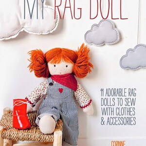 May include: A red-haired rag doll wearing a blue and white striped overall dress and a red bandana. The doll is sitting on a wicker stool with red shoes. The book cover reads "My Rag Doll" and "11 Adorable Rag Dolls to Sew with Clothes & Accessories".