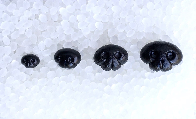 May include: Four black skull-shaped buttons of varying sizes, arranged in a row on a white background.