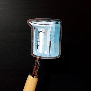 May include: A blue glass beaker with a white ml measurement scale. The beaker is a sticker on a black background.
