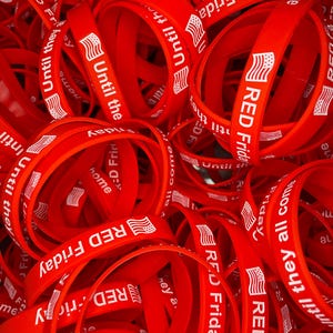 May include: A pile of red silicone wristbands with the text "RED Friday" and "Until they all come home" printed in white. The wristbands also feature a small American flag graphic.