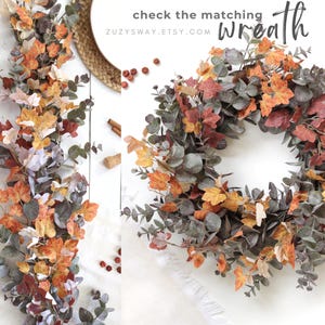 Pode incluir: Uma guirlanda decorativa de outono e uma coroa circular com uma mistura de folhas de bordo laranja, amarelas e vermelhas combinadas com folhagem de eucalipto verde suave. A imagem inclui o texto: check the matching wreath ZUZYSWAY.ETSY.COM.