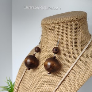May include: A pair of brown wooden bead earrings with silver hooks. The earrings are hanging from a burlap mannequin.