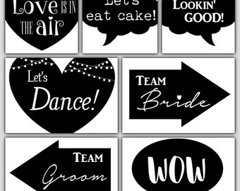 May include: Black and white photo booth props with text such as "Love is in the air", "Let's eat cake", "Lookin' Good", "Let's Dance", "Team Bride", "Team Groom", and "Wow".