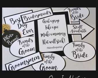 May include: Black and white photo booth props with text that reads "Best Bridesmaids Day Ever", "Friends of the Groom", "Groomsmen", "Family of the Groom", "Grab a prop Take a pic Make a memory That will stick! #hdoodlesparties", "Friends of the Bride", "Still Available", "Family of the Bride", and "OnceInALifetime".