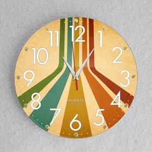 May include: A round, analogue wall clock with a retro design. The clock face has a beige background with colourful stripes radiating from the centre. The numbers are white and the hands are silver.