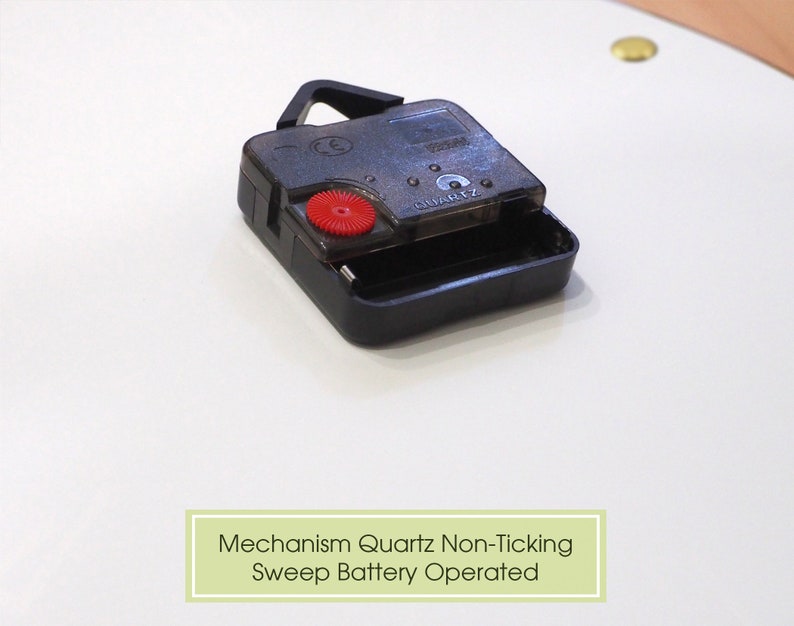 May include: Close-up of a black quartz clock mechanism with a red button. The text "QUARTZ" is visible on the mechanism. Mechanism Quartz Non-Ticking Sweep Battery Operated.