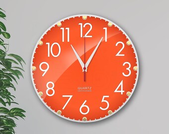 May include: Orange wall clock with white numbers and hands. The clock has a white border and gold accents. The clock face says "QUARTZ silent movement".