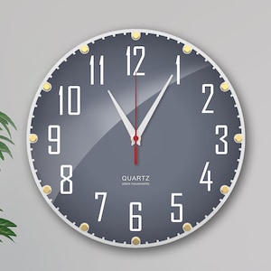 Könnte beinhalten: Eine runde, graue Wanduhr mit goldenen Akzenten und weißen Zahlen. Die Uhr hat einen weißen Minutenzeiger, einen roten Sekundenzeiger und einen weißen Stundenzeiger. Das Zifferblatt der Uhr enthält auch den Text "QUARTZ silent movements".