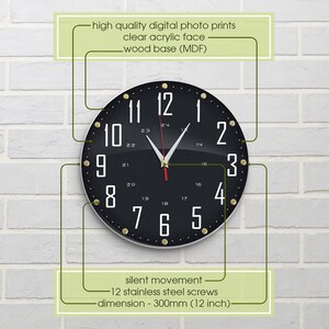 May include: Black and white clock with gold accents and a clear acrylic face. The clock is 12 inches in diameter and has a silent movement. The clock is mounted on a white brick wall.