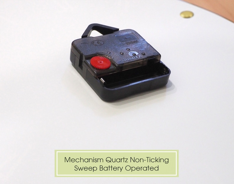 May include: Close-up of a black quartz clock mechanism with a red button. The text "QUARTZ" is visible on the mechanism. Mechanism Quartz Non-Ticking Sweep Battery Operated.