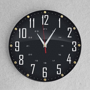May include: A black round clock with gold accents and white numbers. The clock face has a black background with white numbers and a white and red hour and minute hand.