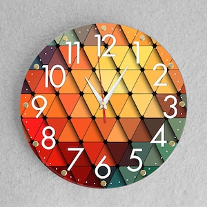 May include: A round clock with a geometric design of orange, red, yellow, and green triangles. The clock face has white numbers and hands.