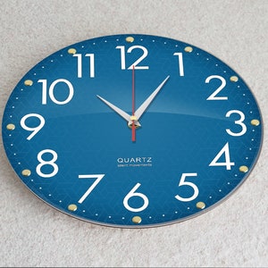 May include: A blue round clock with white numbers and gold accents. The clock face has a geometric pattern. The clock hands are white and red. The clock says "QUARTZ silent movements".