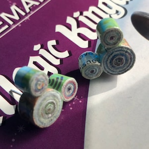 May include: A pair of handmade earrings shaped like the iconic Mickey Mouse silhouette. The earrings are made from rolled up paper, creating a unique and colorful design.