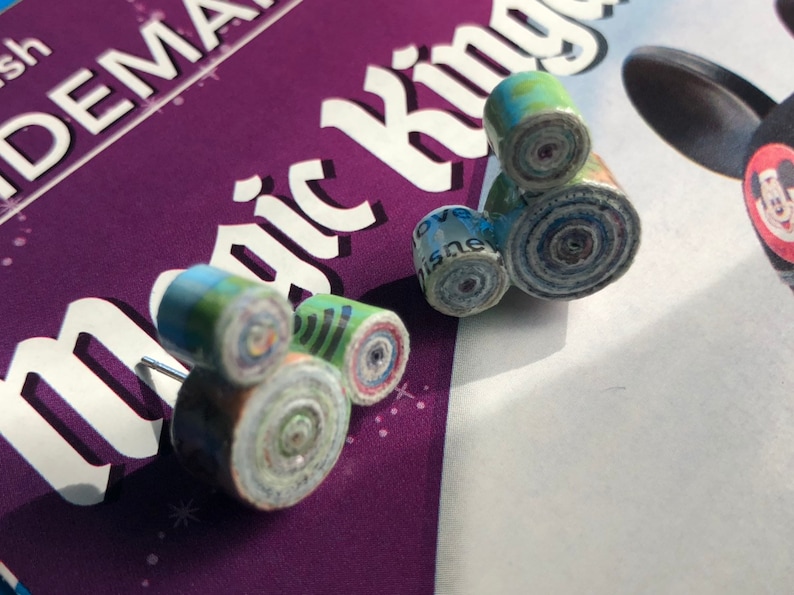 May include: A pair of handmade earrings shaped like the iconic Mickey Mouse silhouette. The earrings are made from rolled up paper, creating a unique and colorful design.