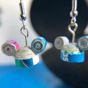 May include: A pair of handmade earrings featuring Mickey Mouse ears made from rolled paper. The ears are blue and pink with a white and green base. The earrings are attached to silver hooks.