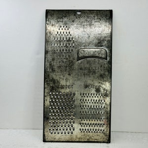May include: Vintage metal grater with four different grating surfaces: shredder, grater, slicer, and a fine grater. The grater is made of silver metal and has a worn, aged look.