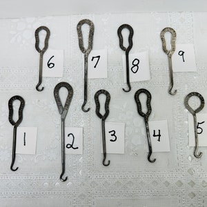 May include: Nine antique metal shoe horn tools with a hook on the end. The tools are numbered 1 through 9.