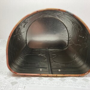 May include: The inside of a metal tin with a silver interior. The tin has a rounded shape and a decorative pattern on the outside.