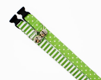 Könnte beinhalten: Zwei grüne Katzenhalsbänder mit Glöckchen. Ein Halsband hat weiße Punkte und das andere weiße Streifen.