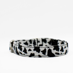Peut inclure: Un collier de chien &agrave; imprim&eacute; vache noir et blanc avec une boucle argent&eacute;e.