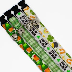 May include: Four St. Patrick's Day themed pet collars with black buckles and silver bells. The collars feature green plaid, shamrocks, rainbows, and the text "Kiss Me I'm Irish".
