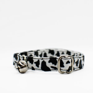 Peut inclure: Un collier de chat imprim&eacute; vache noir et blanc avec une clochette argent&eacute;e et une boucle argent&eacute;e.