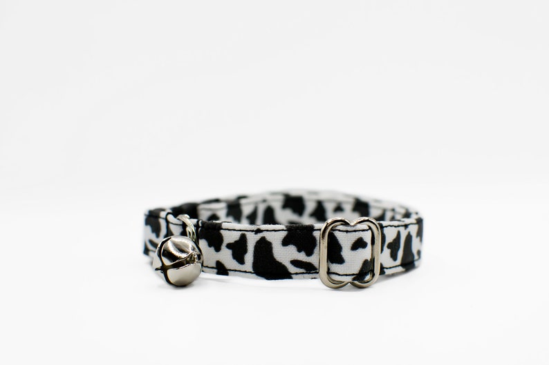 Peut inclure: Un collier de chat imprim&eacute; vache noir et blanc avec une clochette argent&eacute;e et une boucle argent&eacute;e.