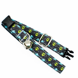 May include: A black cat collar with a green alien pattern and a silver bell. The collar has a black adjustable buckle.