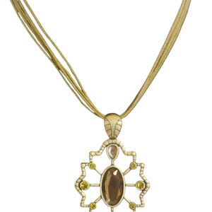 May include: A gold-coloured necklace with a pendant featuring a large brown oval stone at the centre, surrounded by smaller green and clear stones. The necklace has multiple thin gold strands.
