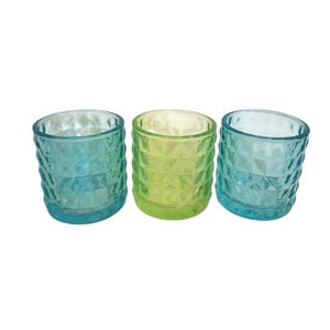 Peut inclure: Trois bougeoirs cylindriques en verre disposés en ligne. Les deux bougeoirs extérieurs sont d'un bleu sarcelle translucide, tandis que celui du centre est d'un vert citron translucide. Chaque pièce en verre présente un motif en losange.