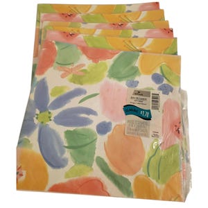 Peut inclure: Un paquet de feuilles de papier cadeau à motifs floraux. Les feuilles présentent un motif aquarelle avec de grandes fleurs et feuilles bleues, oranges, roses et vertes sur fond blanc. Une étiquette est visible sur le papier d'emballage.