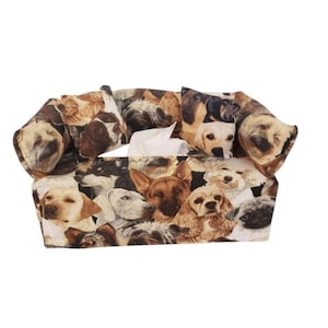 May include: A fabric tissue box cover featuring a collage of various dog breeds in shades of brown, tan, and white. The cover has a rectangular shape with an opening for tissue dispensing. The design includes a variety of dog faces.