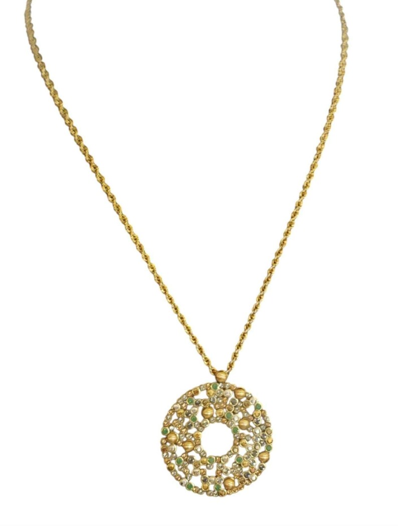 May include: A gold chain necklace with a round pendant. The pendant is made of gold and has a circular design with small green and white stones embedded in it.