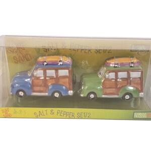 Könnte beinhalten: Ein Salz- und Pfefferset mit zwei Keramik-Kombis mit Surfbrettern auf dem Dach. Einer ist blau und braun, der andere grün und braun. Das Set ist in einer transparenten Kunststoffbox mit den Worten "Surf & Sand" und "Salt & Pepper Set 1/2" verpackt.