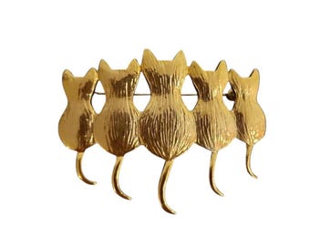 Broche vintage dourado com cinco gatos sentados em fila, representando gatinhos.