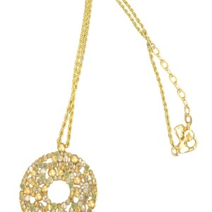 May include: A gold-coloured necklace featuring a circular pendant. The pendant is decorated with small, round beads in gold, green, and clear hues. The chain has a twisted rope design, and the clasp is visible.
