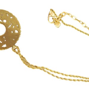 May include: A gold necklace with a circular, openwork pendant and a central hole. The pendant is attached to a fine chain. The necklace is shown against a white backdrop.